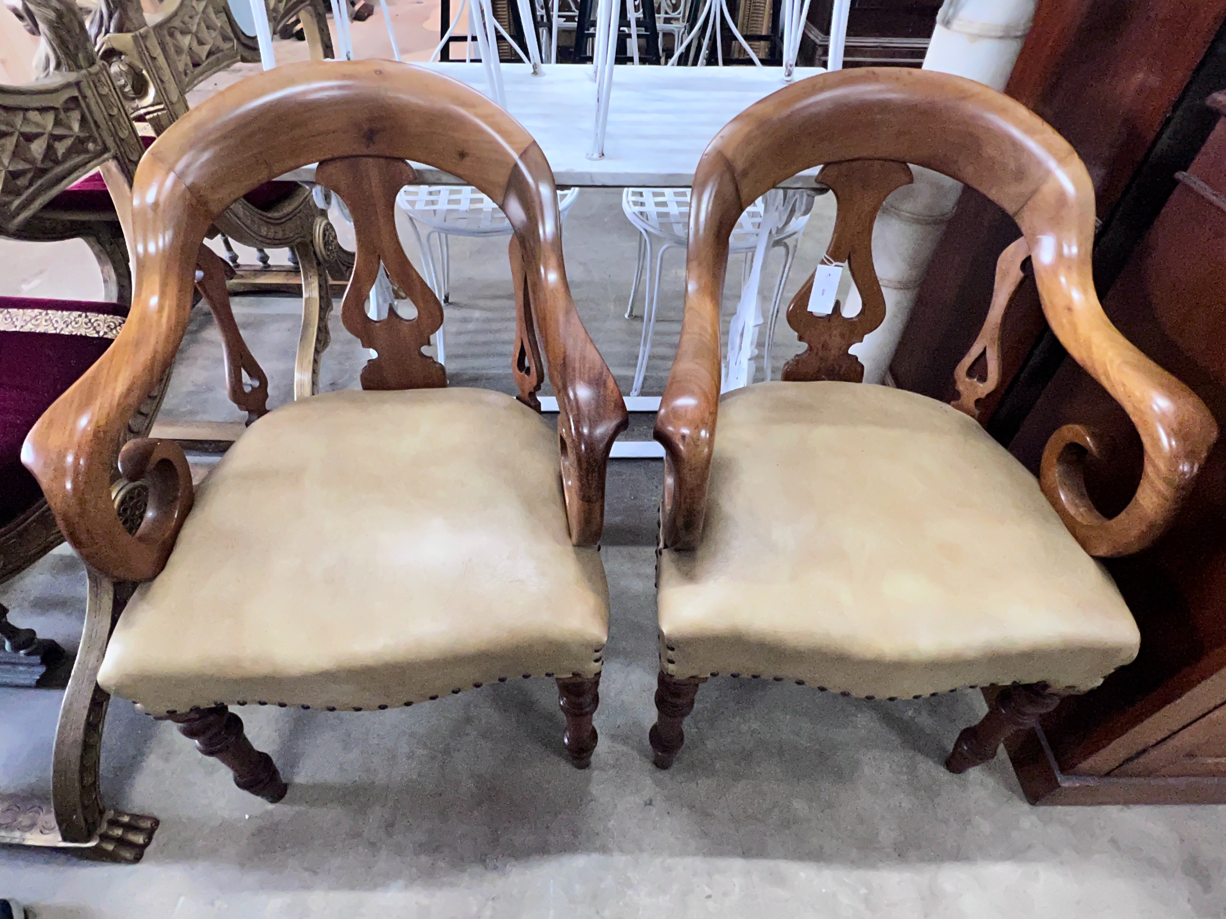 A pair of Victorian walnut elbow chairs with light brown leather seats, width 59cm, depth 51cm, height 90cm